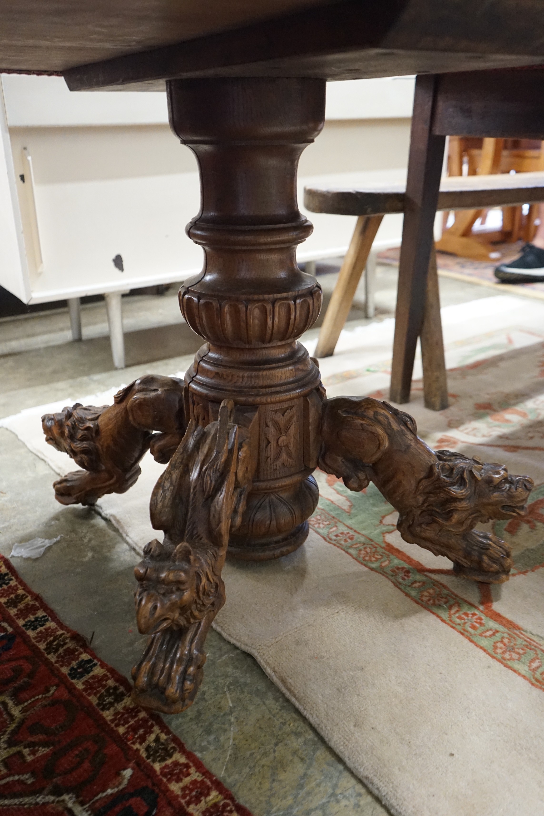An early 20th century Continental carved oak circular centre table with heraldic tapestry top on winged lion supports, diameter 102cm, height 74cm